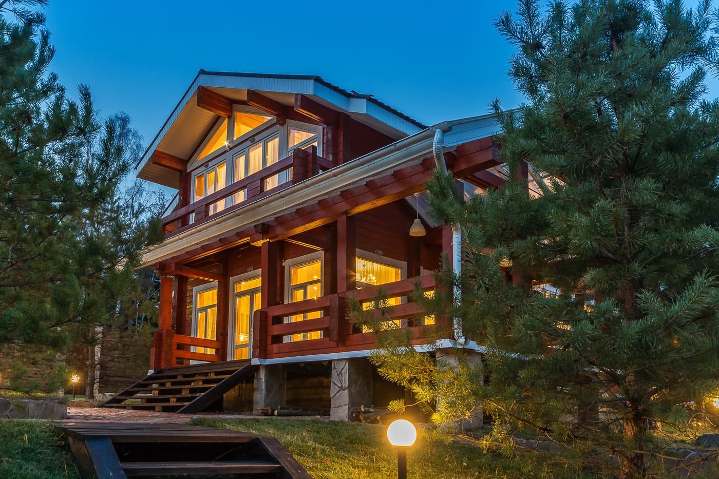 Premium log home illuminated at dusk among pine trees